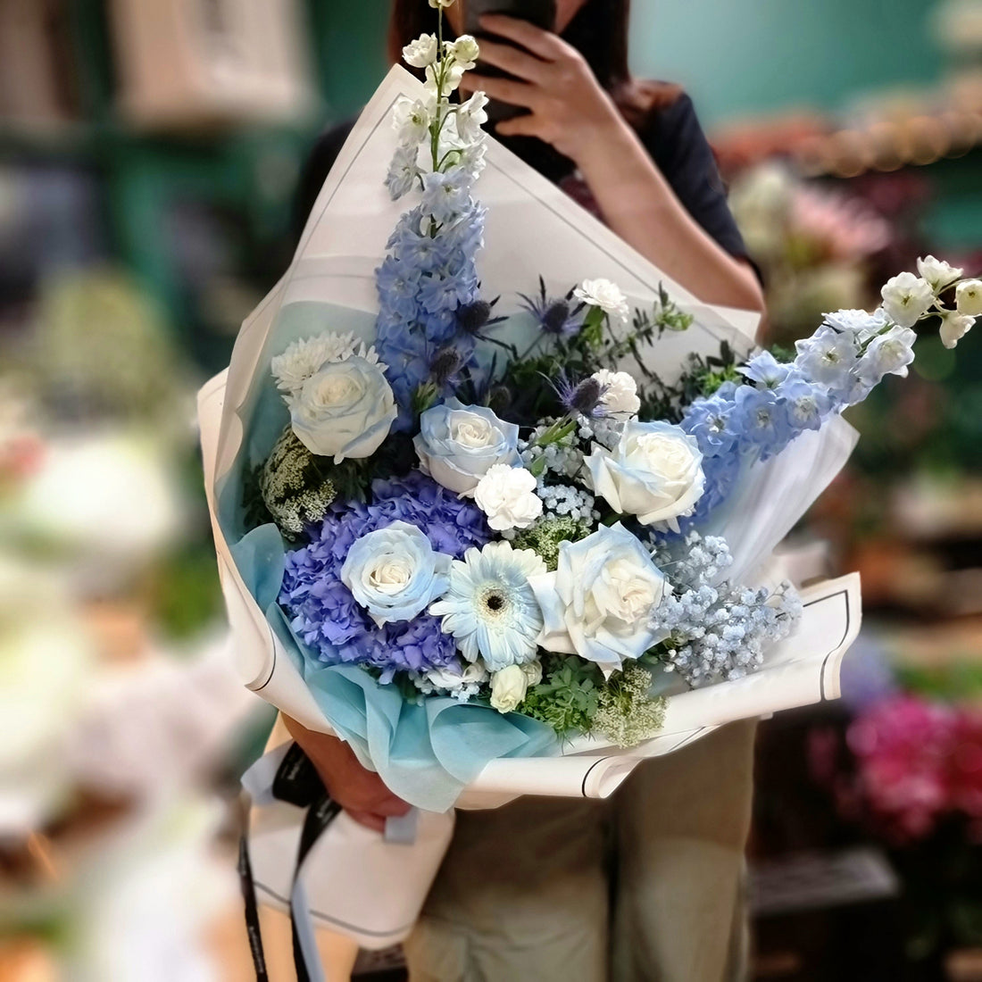 Lilian Ding holding a bespoke blue and white bouquet at Flowerland studio in Nunuwading. Same-day flower delivery service in Melbourne's Eastern Suburbs. 