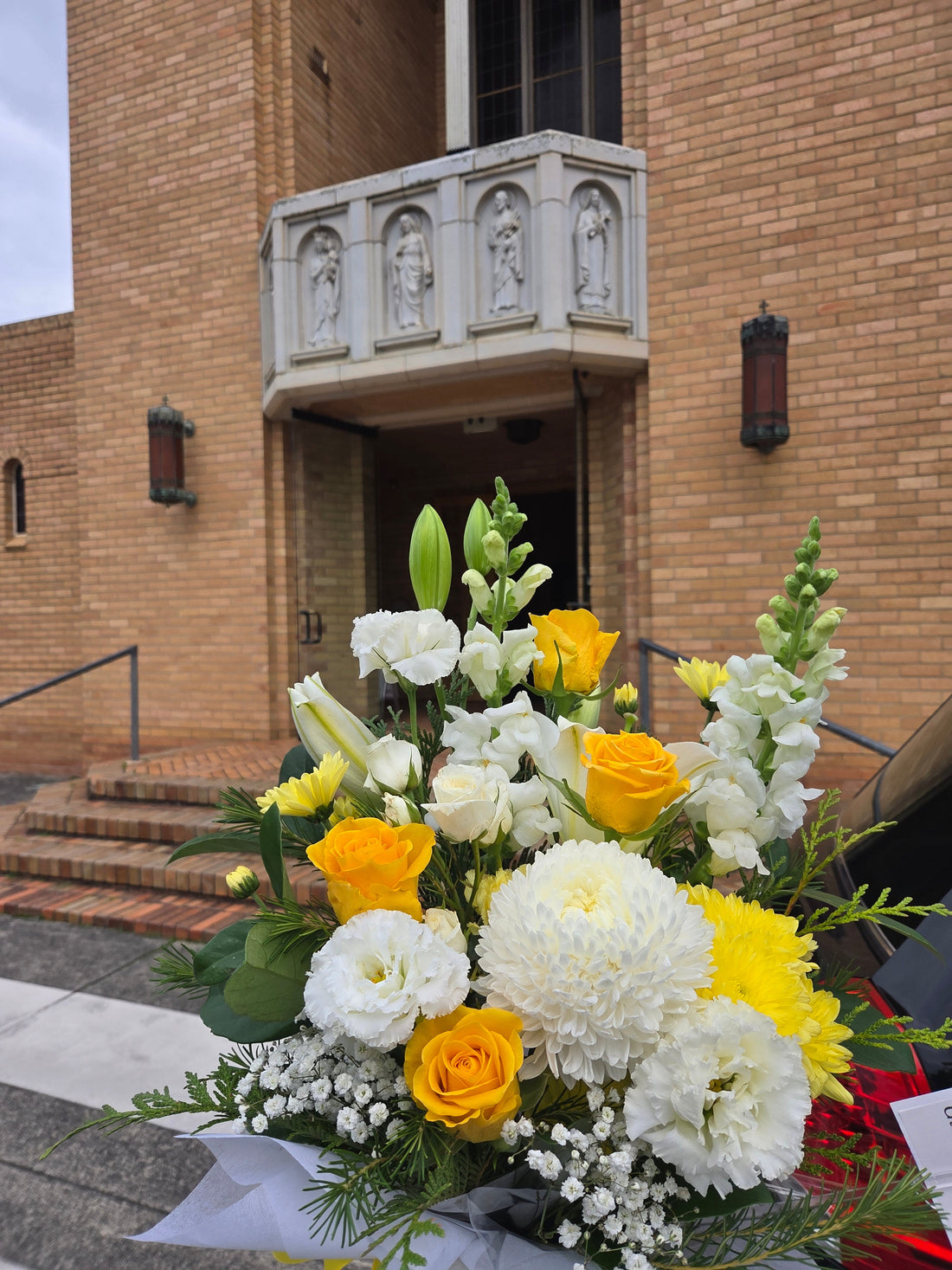 Elegant yellow and white sympathy bouquet for funeral service at Sacred Heart Parish, Croydon, delivered with care by Flowerland.