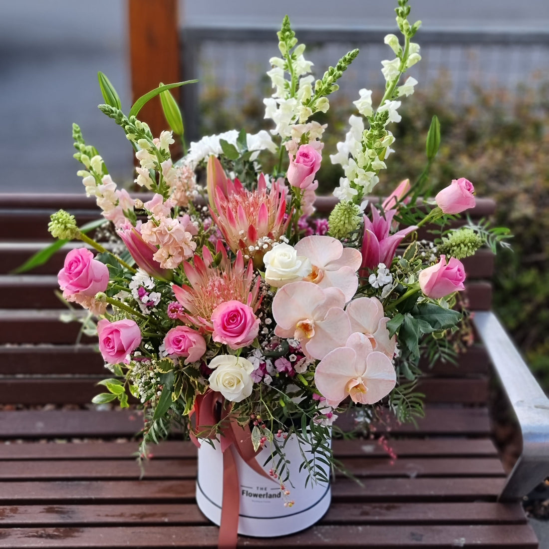 "Same-day flower delivery in Doncaster: A lush floral arrangement in a hat box, featuring white orchids and pink roses, expertly crafted for a local family in the Doncaster area."