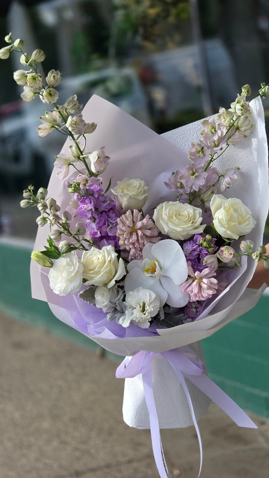 Artisan bespoke floral bouquet with white orchids, roses, and lavender delphiniums. Hand-crafted at Flowerland Nunawading studio for a premium customized gift in Melbourne’s eastern suburbs.