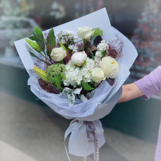 A sophisticated artisan bouquet featuring white roses and elegant lilies, handcrafted by The Flowerland.
