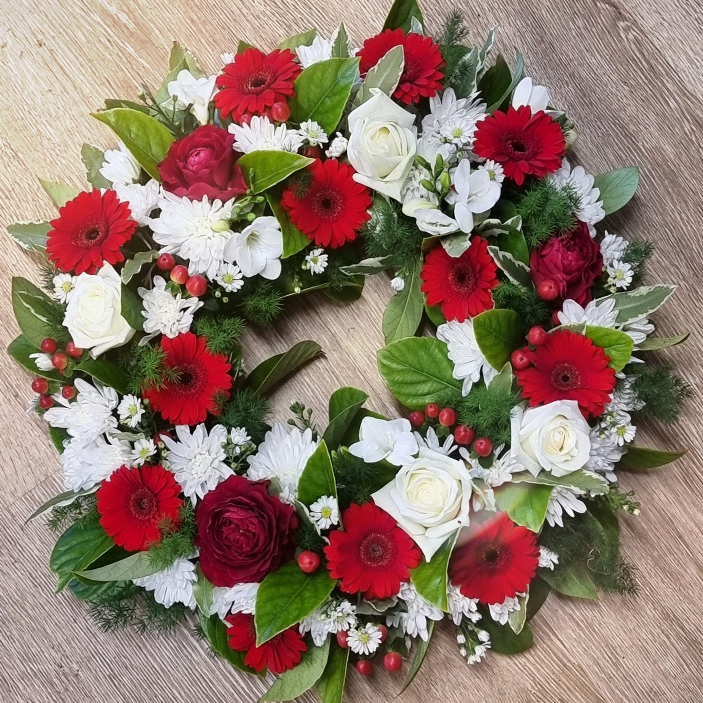 Traditional round Fresh Flower Wreath featuring a respectful mix of fresh red and white blossoms with rich green foliage same-day delivery The Flowerland Nunawading