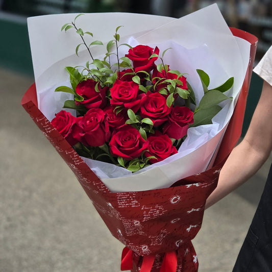 Beautiful long stem premium red roses mixed with lush green foliage wrapped in romantic Valentines Day paper same-day delivery The Flowerland Nunawading