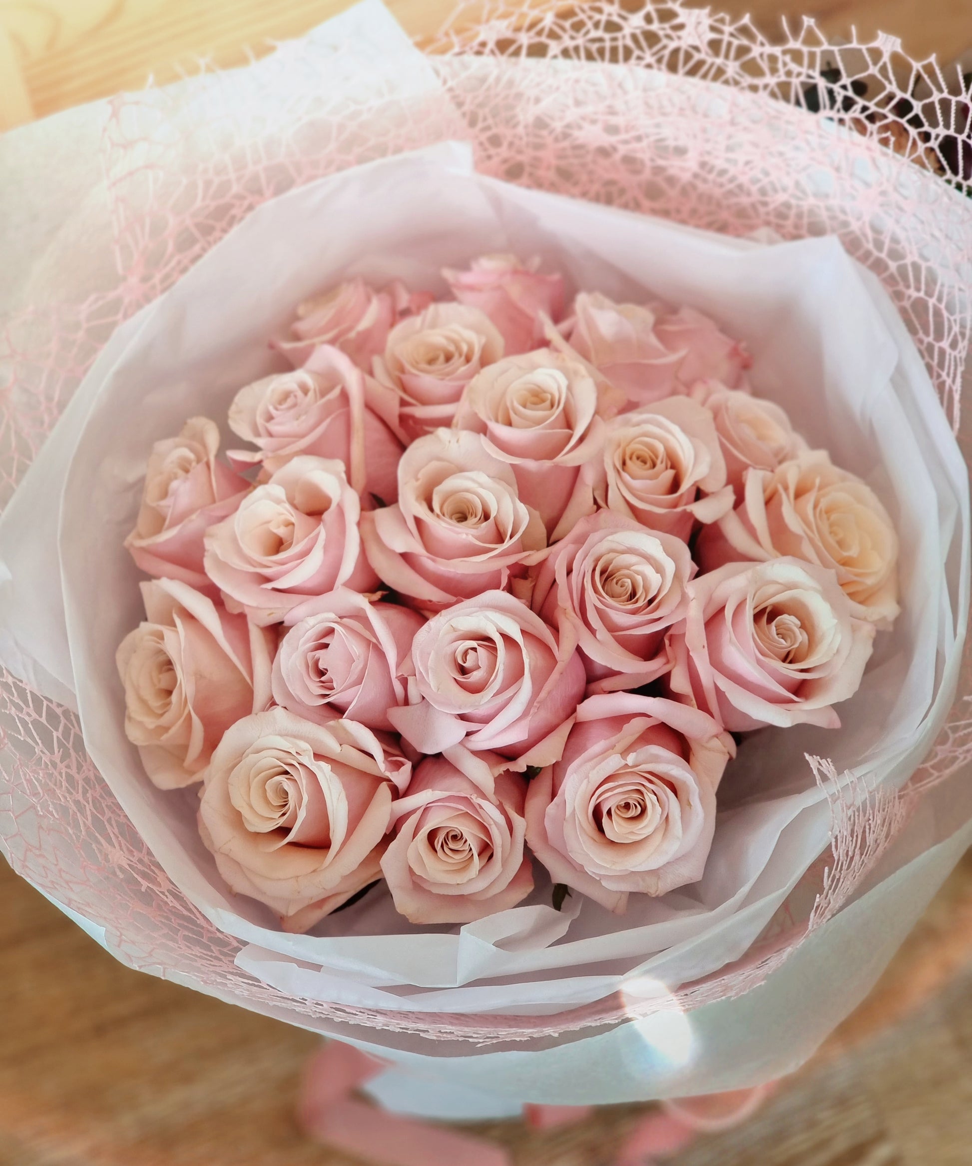 Top close up view of fresh pink rose bouquet wrapped in elegant mesh layers for gift delivery near Knox.